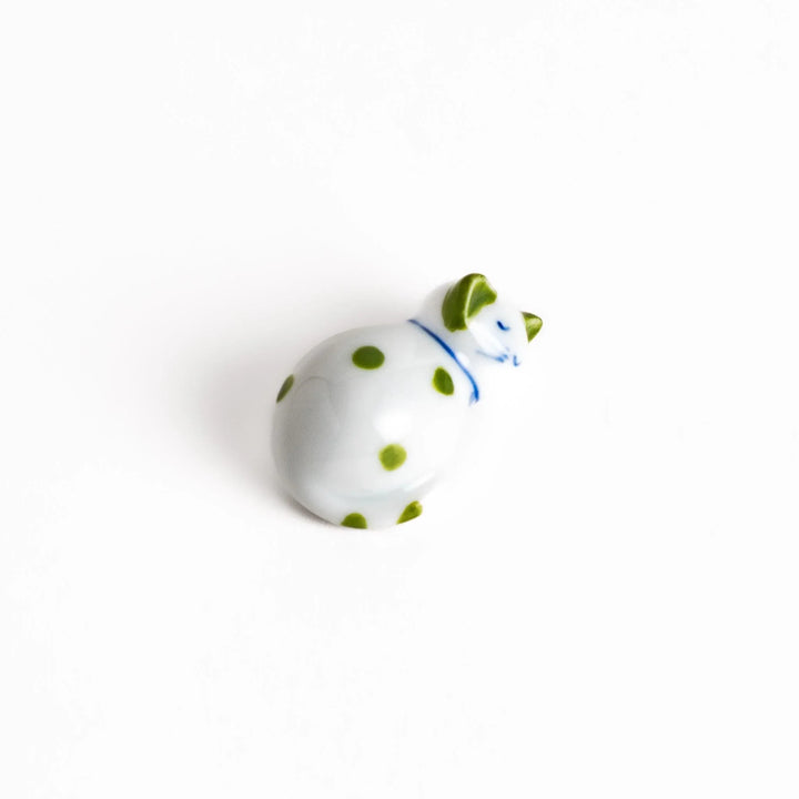 White ceramic cat chopstick rest with green dots in sleeping pose bringing natural charm to table.