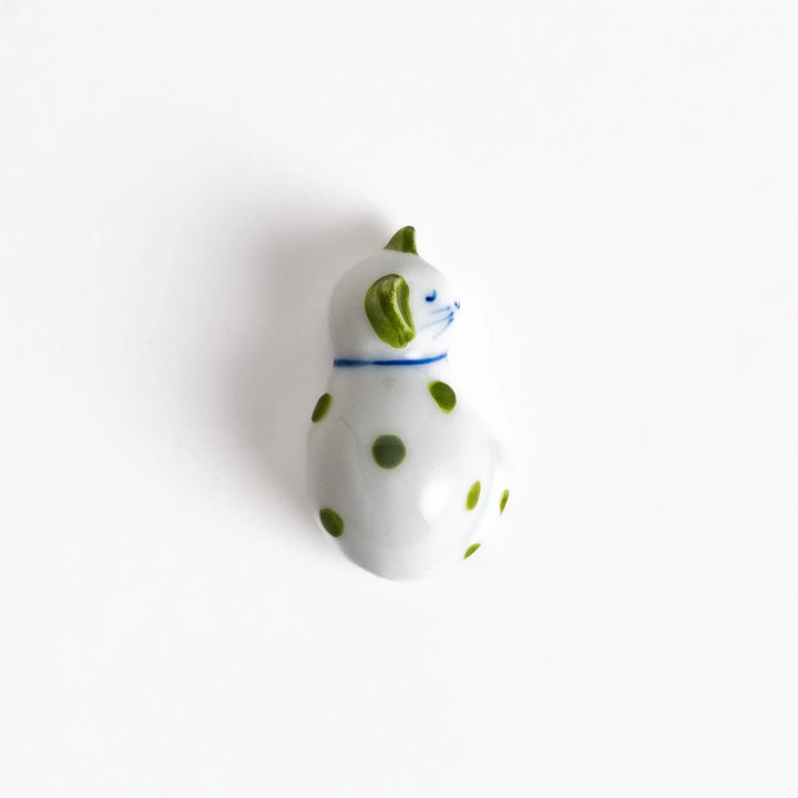 White ceramic cat chopstick rest with green dots in sleeping pose bringing natural charm to table.