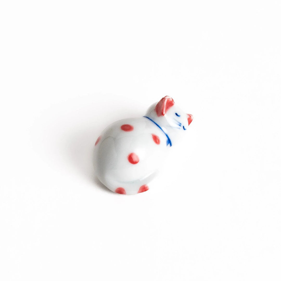 Adorable white ceramic chopstick rest shaped like a sleeping cat with red dots, adding a playful touch to your table setting.