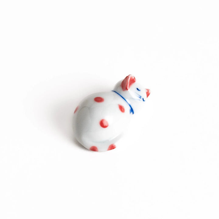 Adorable white ceramic chopstick rest shaped like a sleeping cat with red dots, adding a playful touch to your table setting.