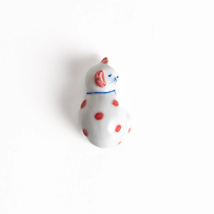 Adorable white ceramic chopstick rest shaped like a sleeping cat with red dots, adding a playful touch to your table setting.