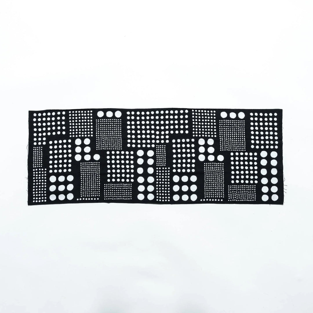 Polka dot tenugui hand towel laid flat, showcasing an arrangement of white dots on black fabric.