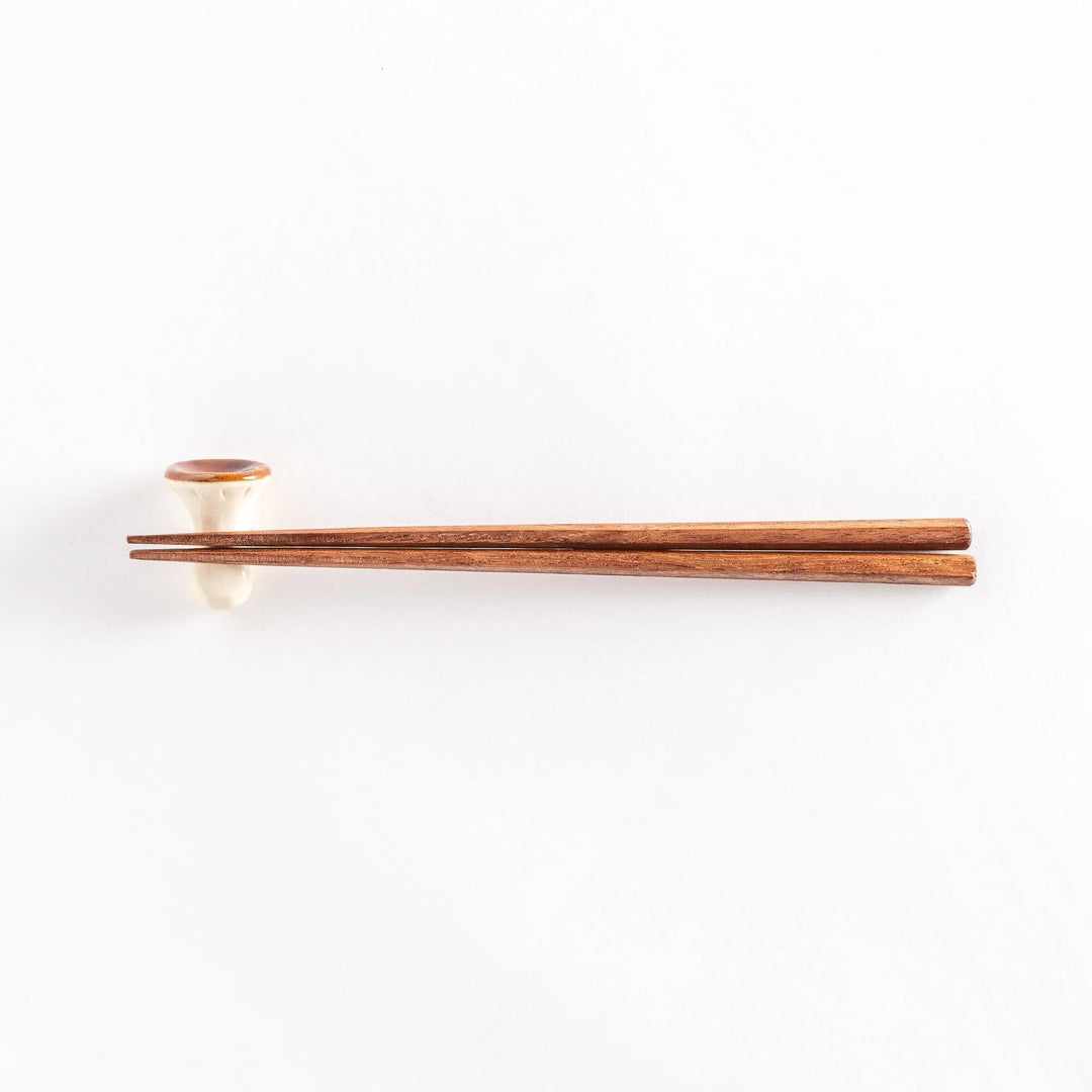 Porcini mushroom chopsticks rest with chopsticks placed on top, photographed from a distance.
