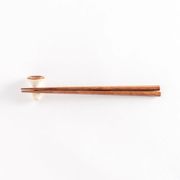 Porcini mushroom chopsticks rest with chopsticks placed on top, photographed from a distance.
