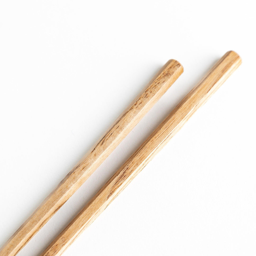 Three pairs of natural chestnut wood chopsticks, each with a different geometric shape—triangle, hexagon, and round.