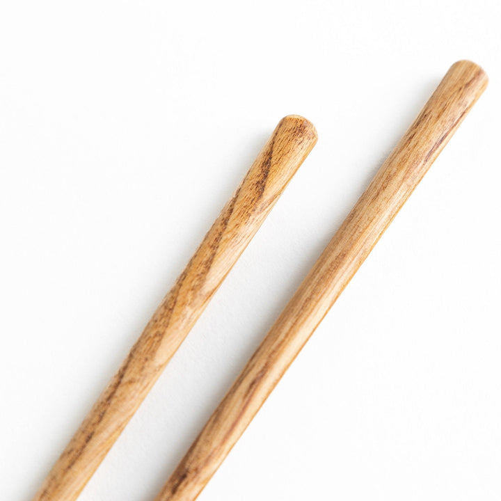 Three pairs of natural chestnut wood chopsticks, each with a different geometric shape—triangle, hexagon, and round.