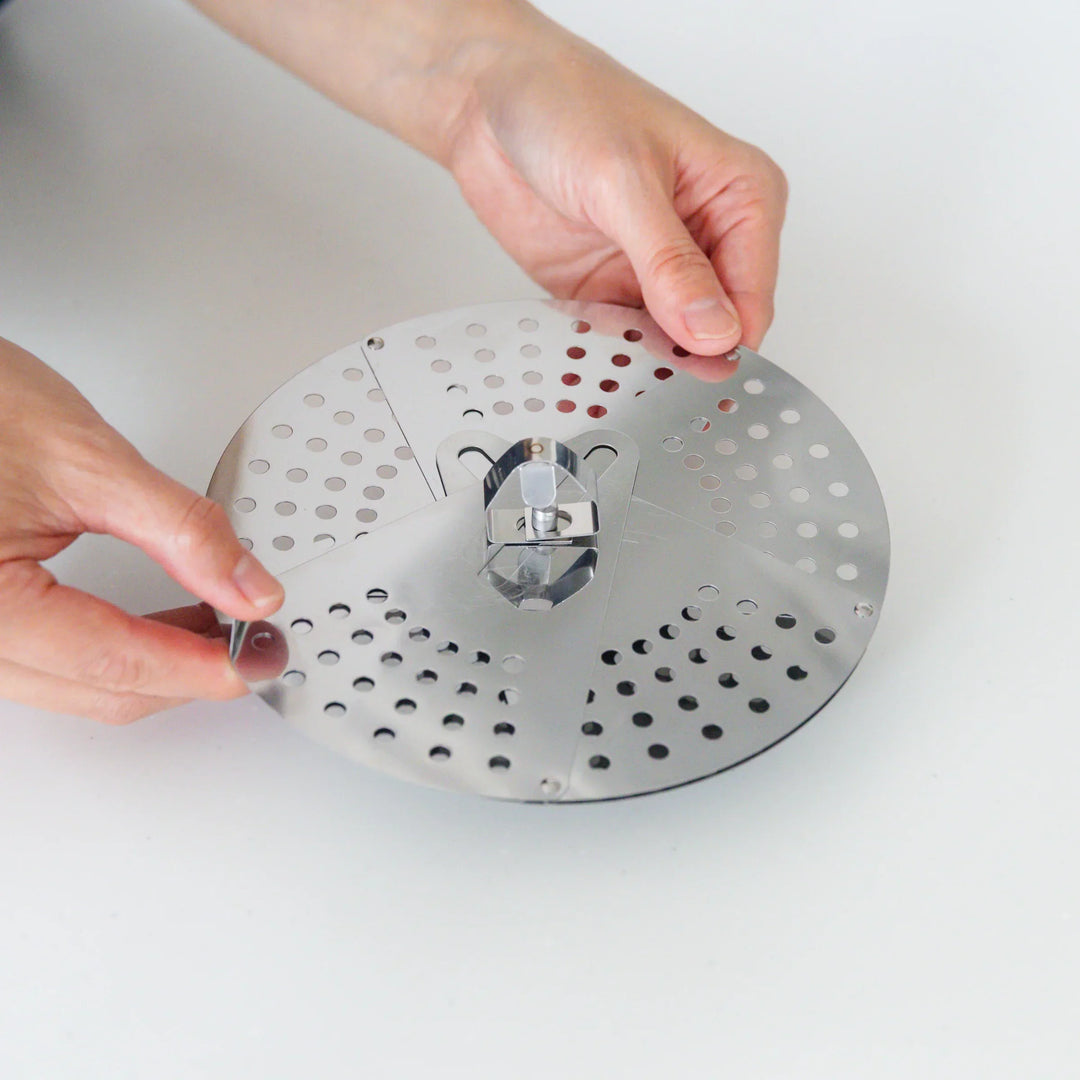 Adjustable stainless steel drop lid with foldable petals for steaming simmering and boil over control.