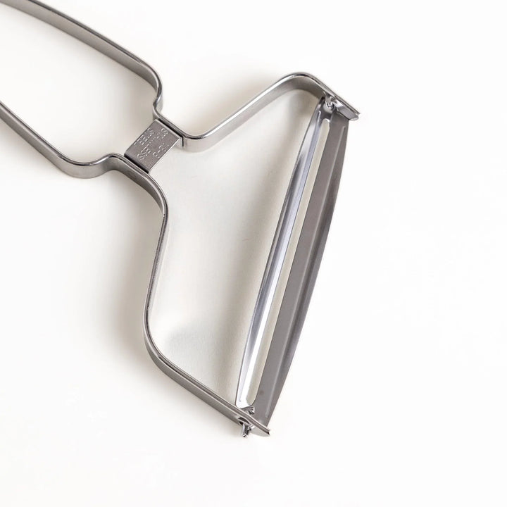 Stainless steel peeler with sharp blade and ergonomic handle for peeling fruits and vegetables easily.