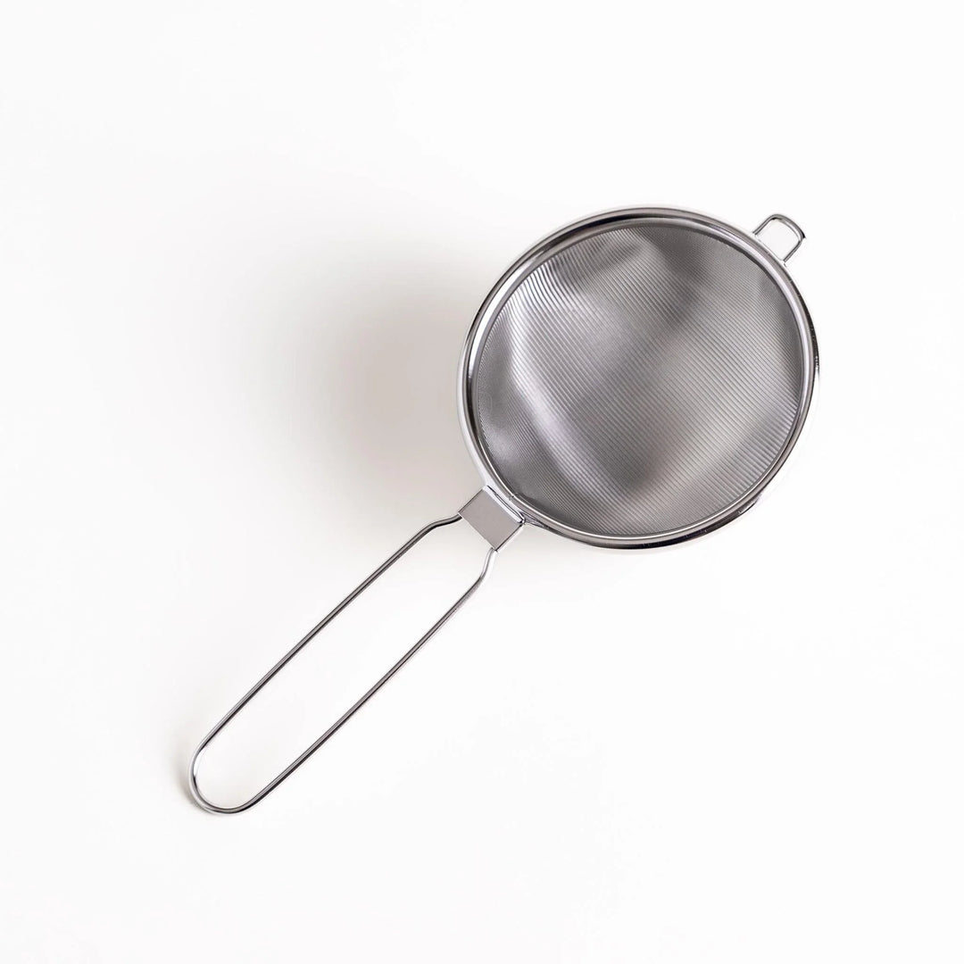 Stainless steel tea strainer with a fine mesh and a long handle, an essential kitchenware tool for brewing loose leaf tea.