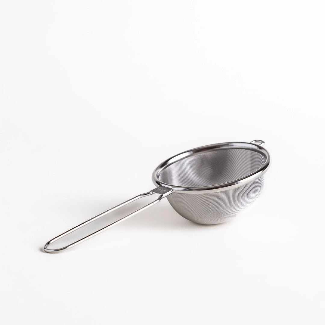 Stainless steel tea strainer with a fine mesh and a long handle, an essential kitchenware tool for brewing loose leaf tea.