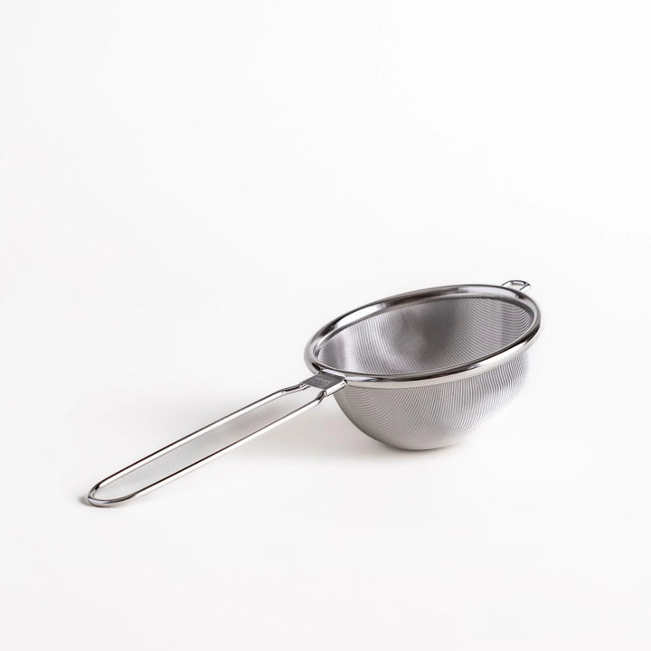 Stainless steel tea strainer with a fine mesh and a long handle, an essential kitchenware tool for brewing loose leaf tea.