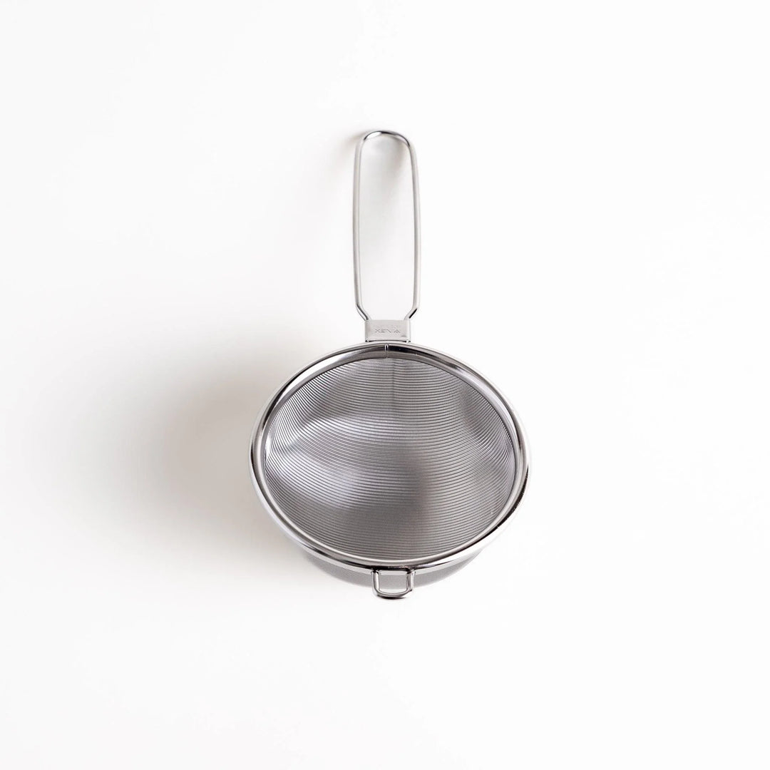 Stainless steel tea strainer with a fine mesh and a long handle, an essential kitchenware tool for brewing loose leaf tea.