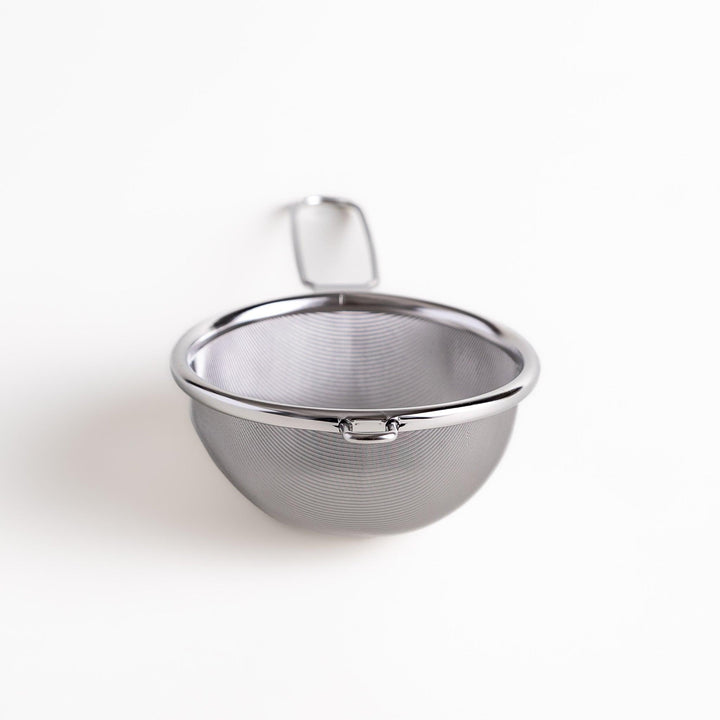 Stainless steel tea strainer with a fine mesh and a long handle, an essential kitchenware tool for brewing loose leaf tea.
