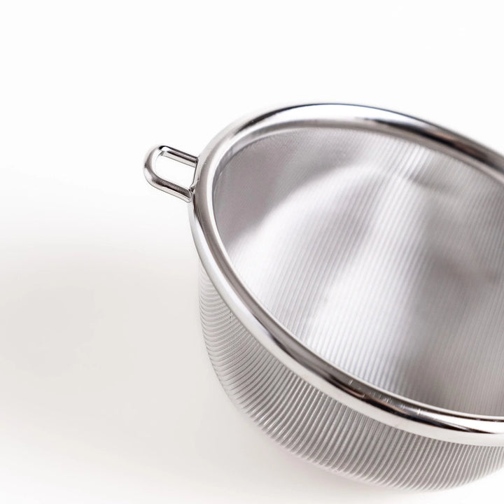 Stainless steel tea strainer with a fine mesh and a long handle, an essential kitchenware tool for brewing loose leaf tea.