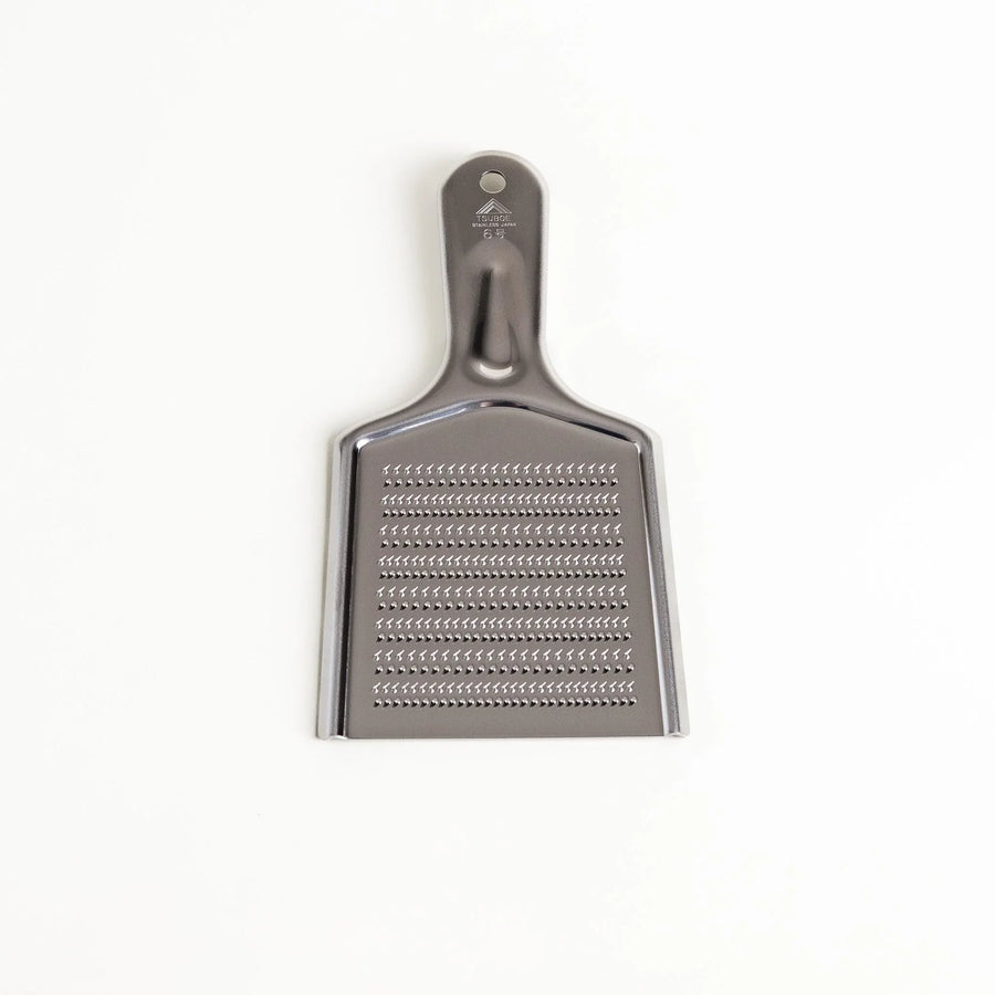 Stainless steel grater with sharp blades and ergonomic handle ideal for cheese vegetables and spices.