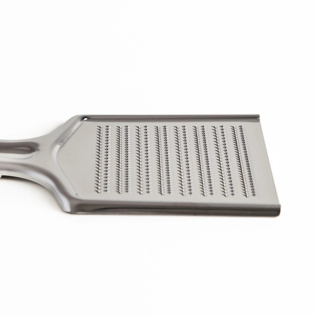 Stainless steel grater with sharp blades and ergonomic handle ideal for cheese vegetables and spices.