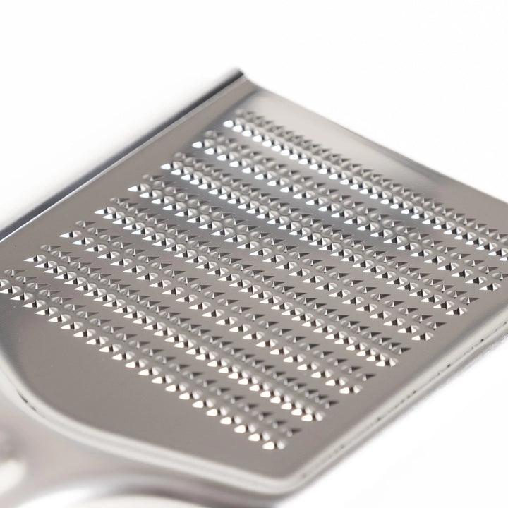 Stainless steel grater with sharp blades and ergonomic handle ideal for cheese vegetables and spices.