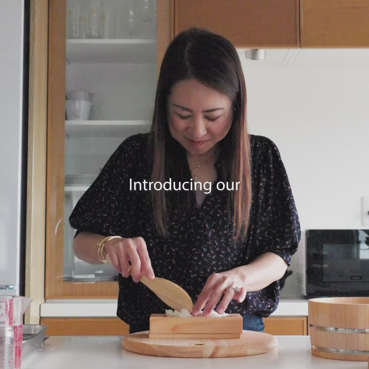 Molding triangle rice balls with a traditional japanese hinoki wood onigiri mold for authentic bento lunch preparation