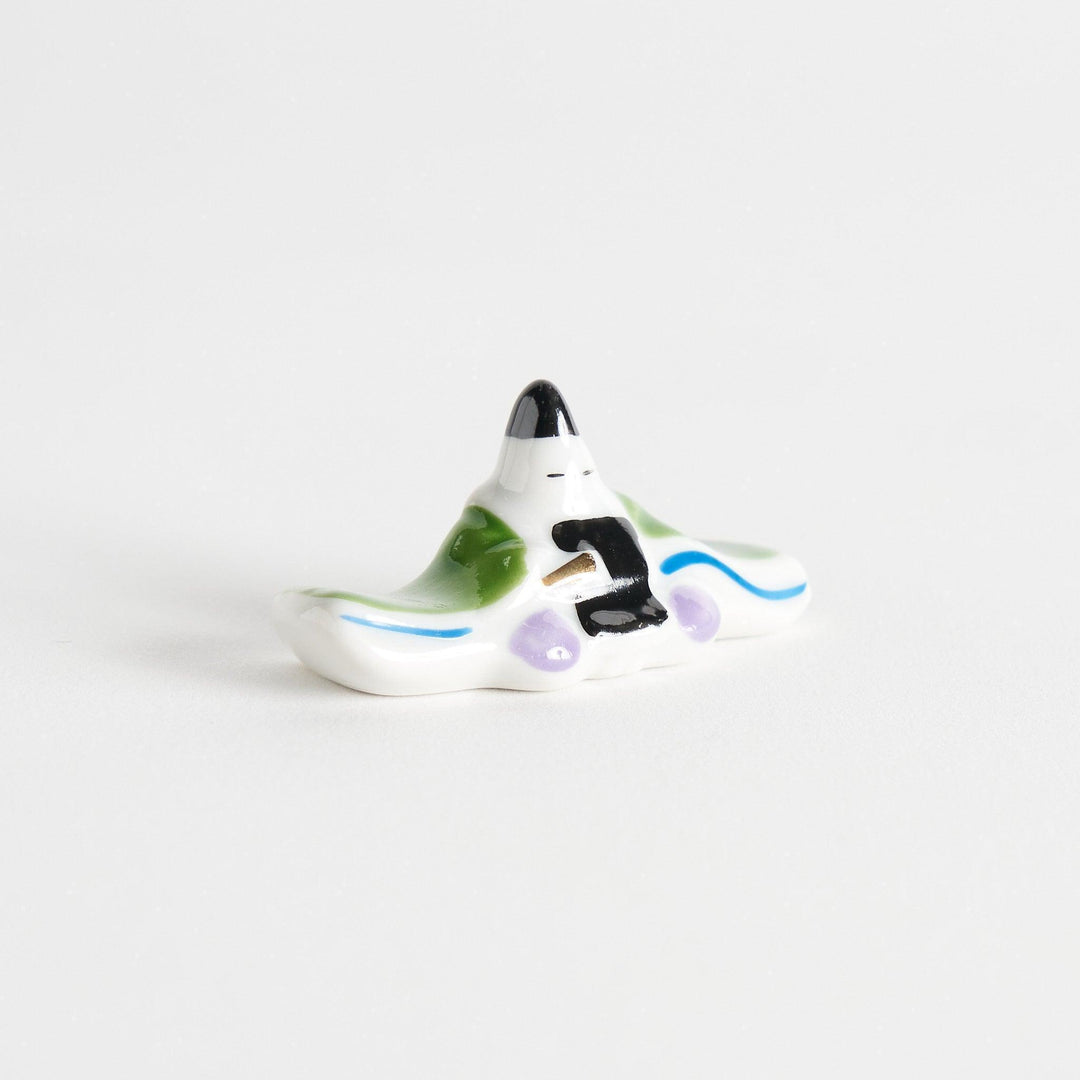 A ceramic chopstick rest shaped like a Japanese prince, painted in orange with floral accents.