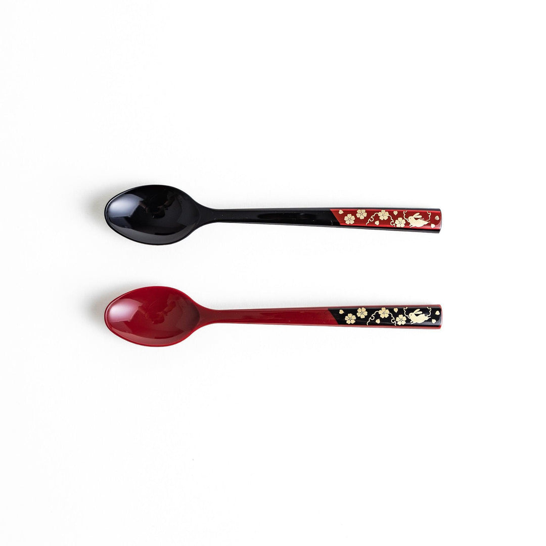 A set of two coffee spoons, one red and one black, with gold floral designs on the handles.