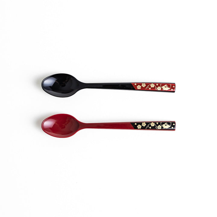 A set of two coffee spoons, one red and one black, with gold floral designs on the handles.