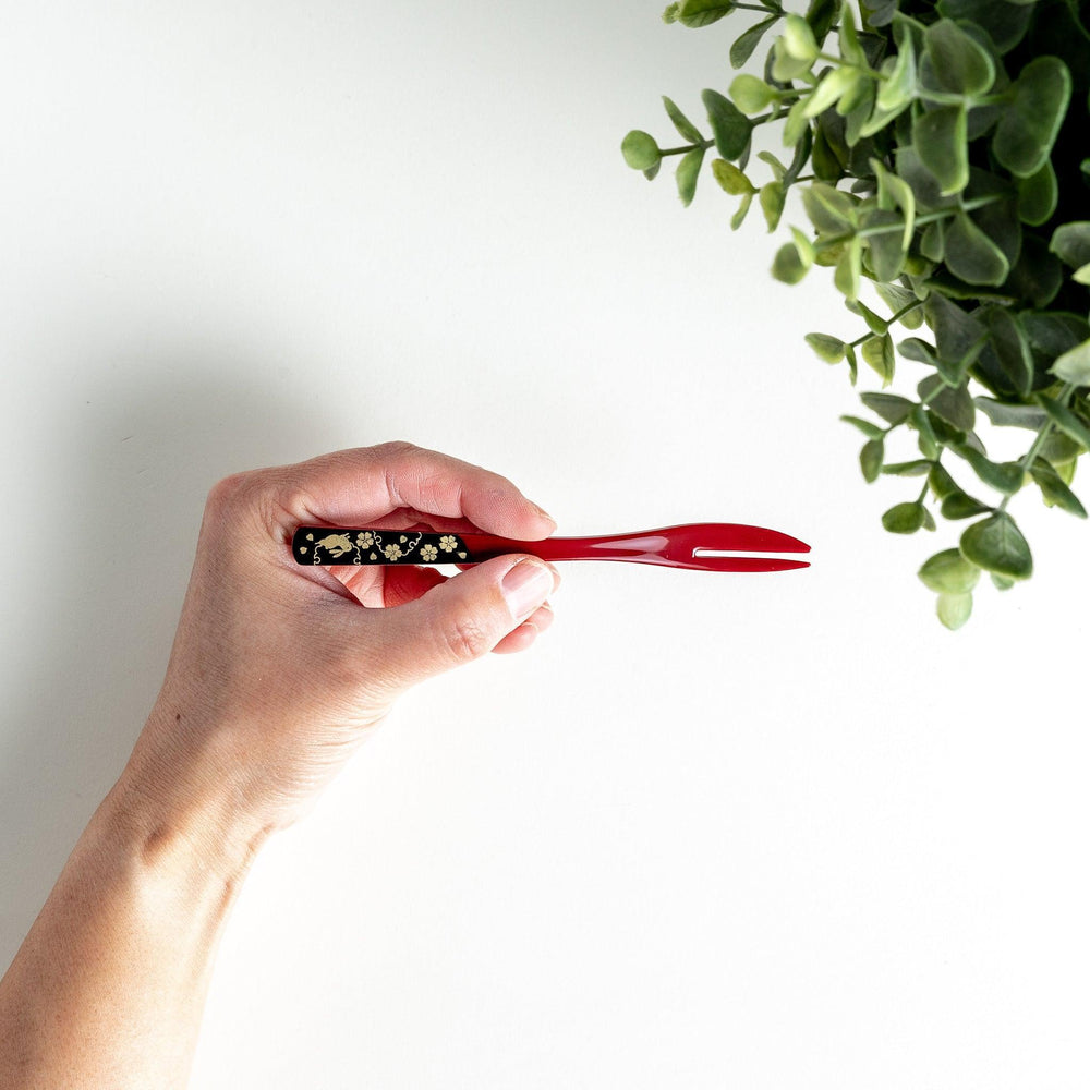 A set of two dessert forks, one red and one black, with rabbit designs on the handles.