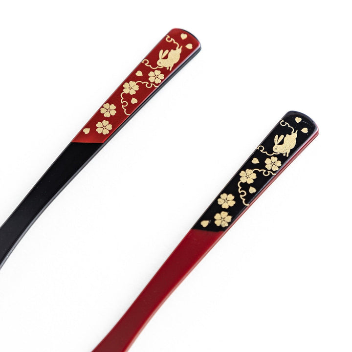 A set of two dessert forks, one red and one black, with rabbit designs on the handles.