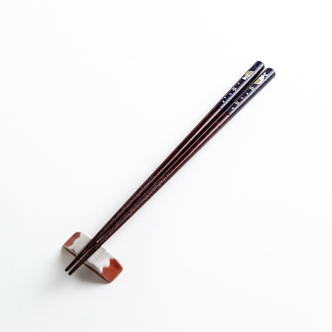 A pair of lacquered chopsticks adorned with floral patterns and rabbit. Available in purple or red.