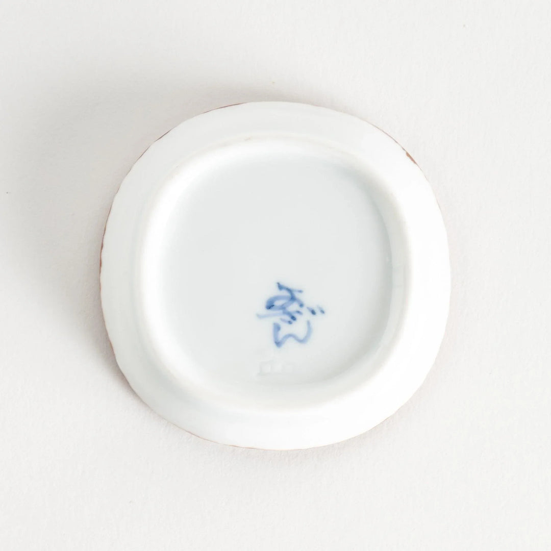 Bottom view of the sauce dish, displaying the manufacturer's mark in blue ink on a smooth surface.