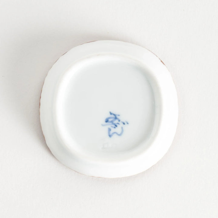 Bottom view of the sauce dish, displaying the manufacturer's mark in blue ink on a smooth surface.