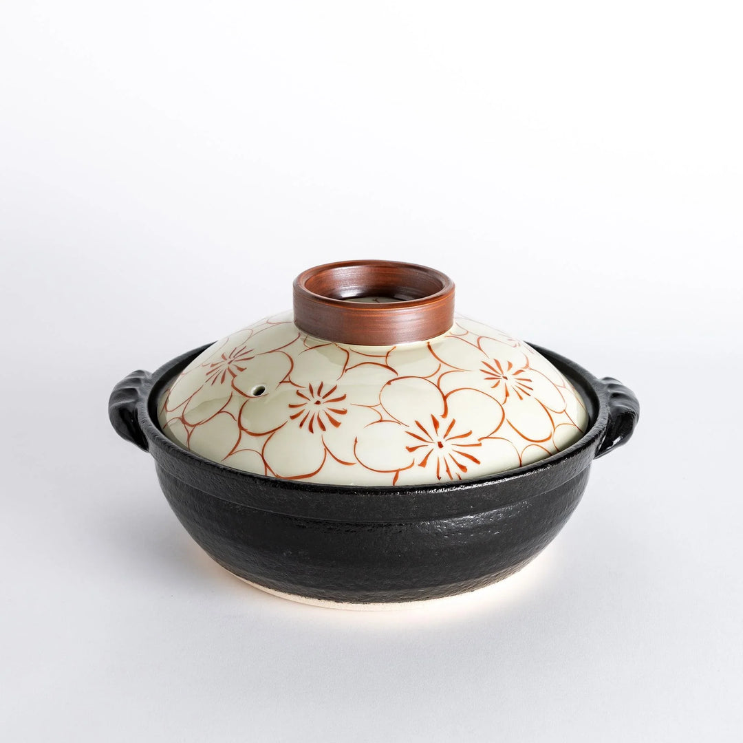 A 8-inch donabe with a vibrant red blossom pattern lid and black pot.