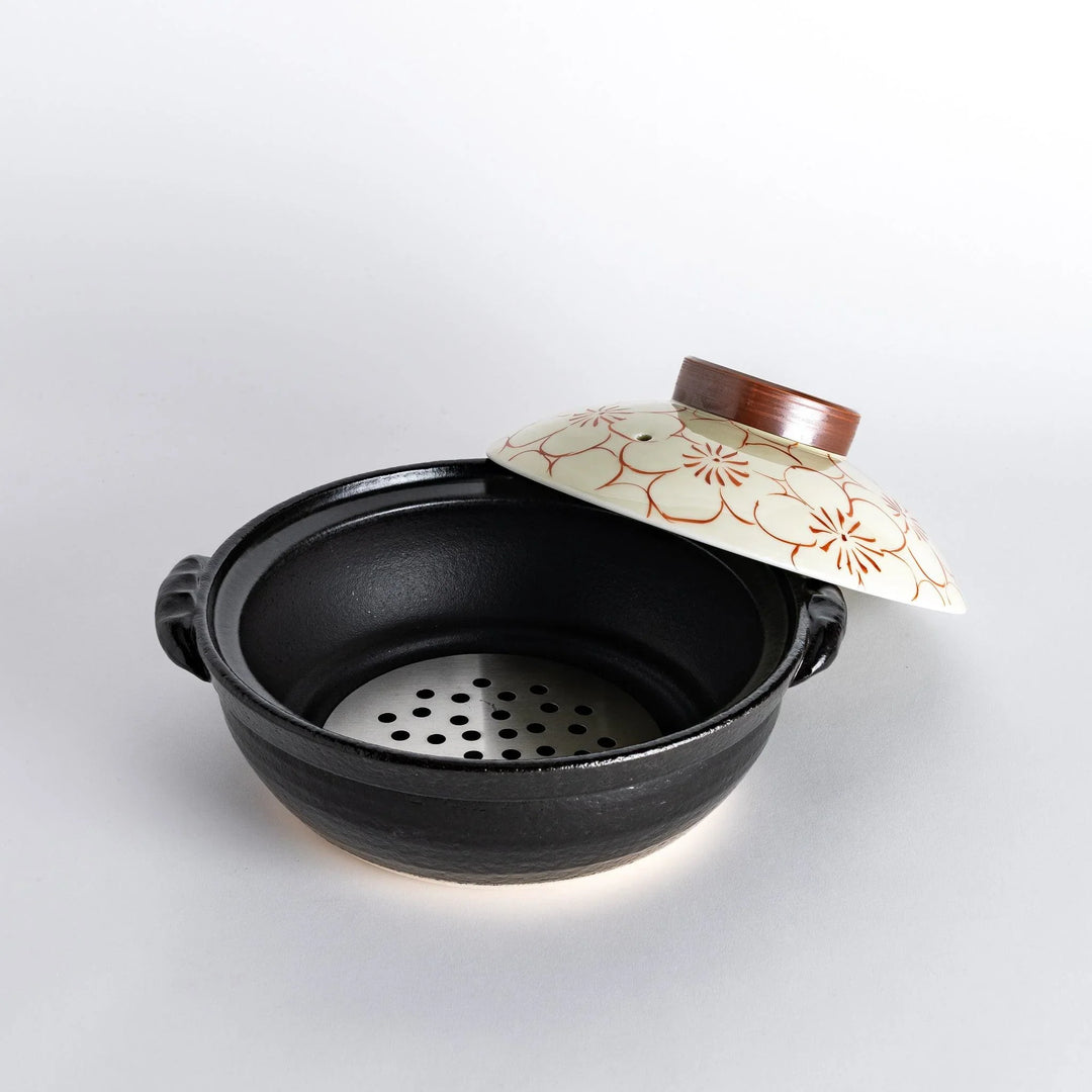 A 8-inch donabe with a vibrant red blossom pattern lid and black pot.
