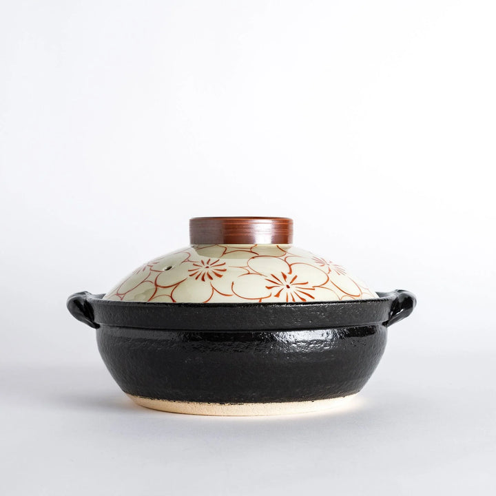 A 8-inch donabe with a vibrant red blossom pattern lid and black pot.