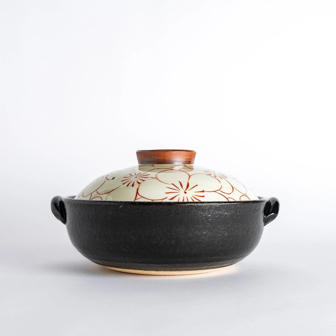 A donabe with a vibrant red floral pattern on white lid and black pot.