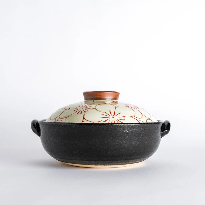A donabe with a vibrant red floral pattern on white lid and black pot.