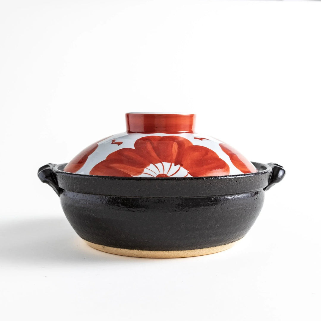 Side profile of the donabe, highlighting its sturdy black base and vibrant floral lid, a striking piece for your table.