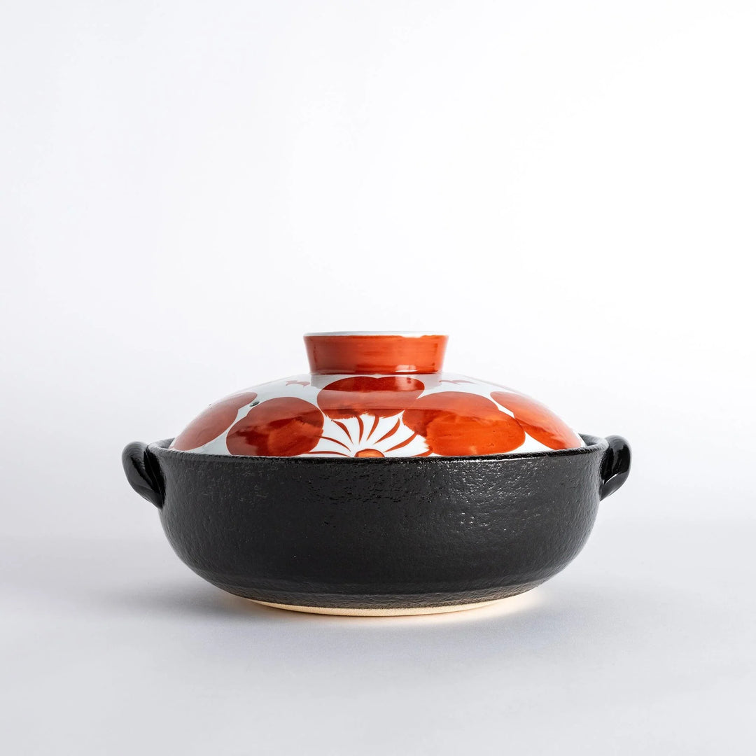 Side profile of the donabe, highlighting its sturdy black base and vibrant floral lid, a striking piece for your table.
