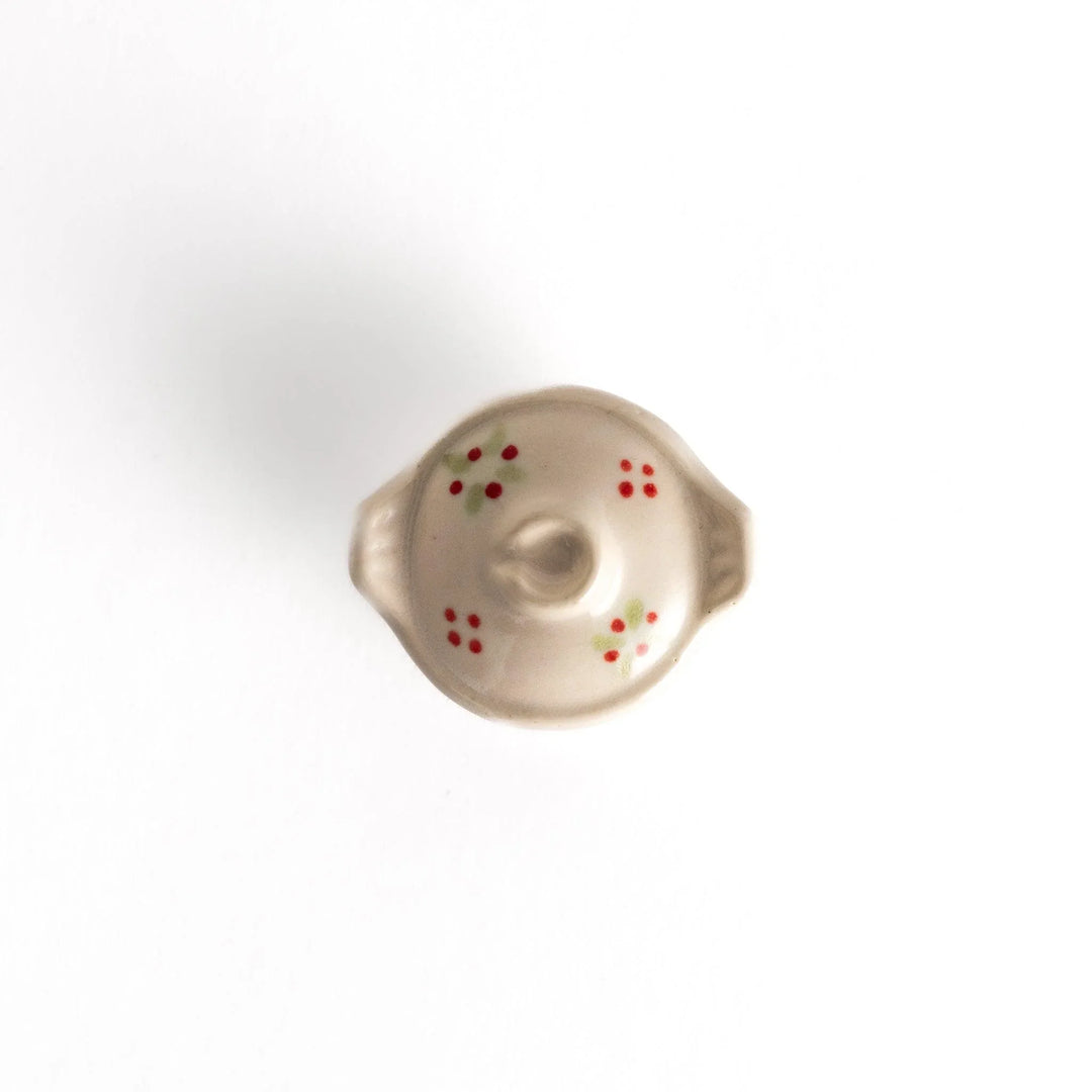 Top view of the earthen pot-shaped chopsticks rest, displaying its floral motif, rounded lid, and handle-like features.