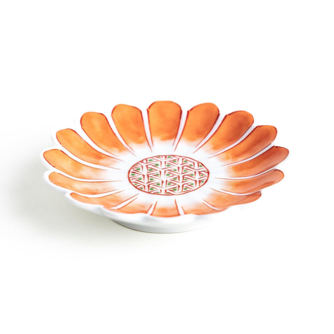 A small, scalloped-edge porcelain dish with orange chrysanthemum petal designs and a geometric center.