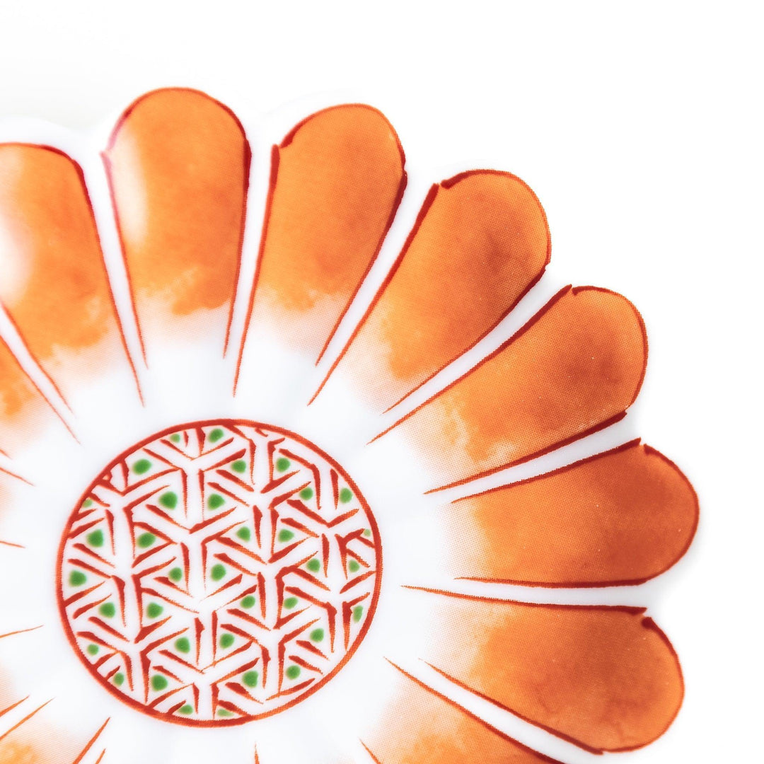 A small, scalloped-edge porcelain dish with orange chrysanthemum petal designs and a geometric center.