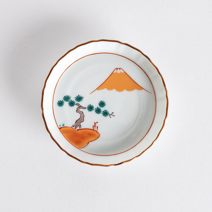 Round Japanese ceramic dish with Mount Fuji and red pine grove design scalloped edge and orange rim.
