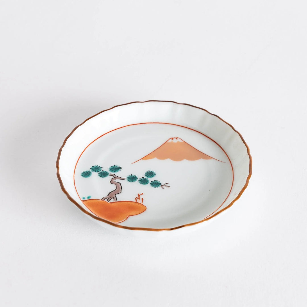Round Japanese ceramic dish with Mount Fuji and red pine grove design scalloped edge and orange rim.