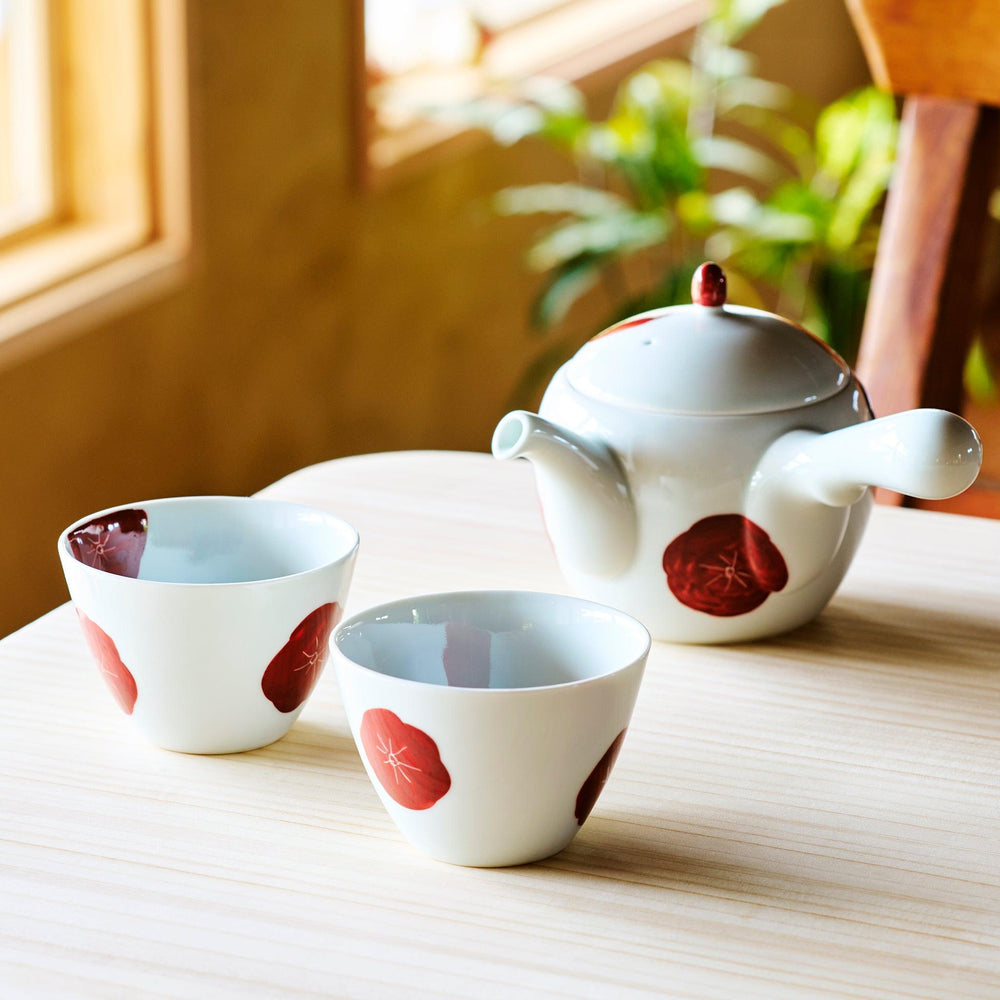 White porcelain Japanese tea set with hand-painted red plum blossoms, featuring one teapot and two matching cups.