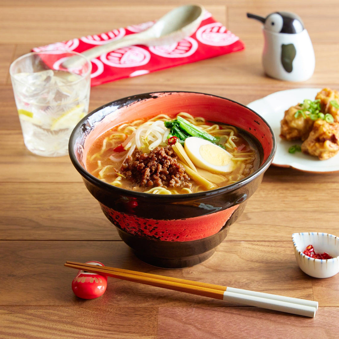 Ramen bowl with miso ramen, served with chopsticks; fried chicken and water in the background.