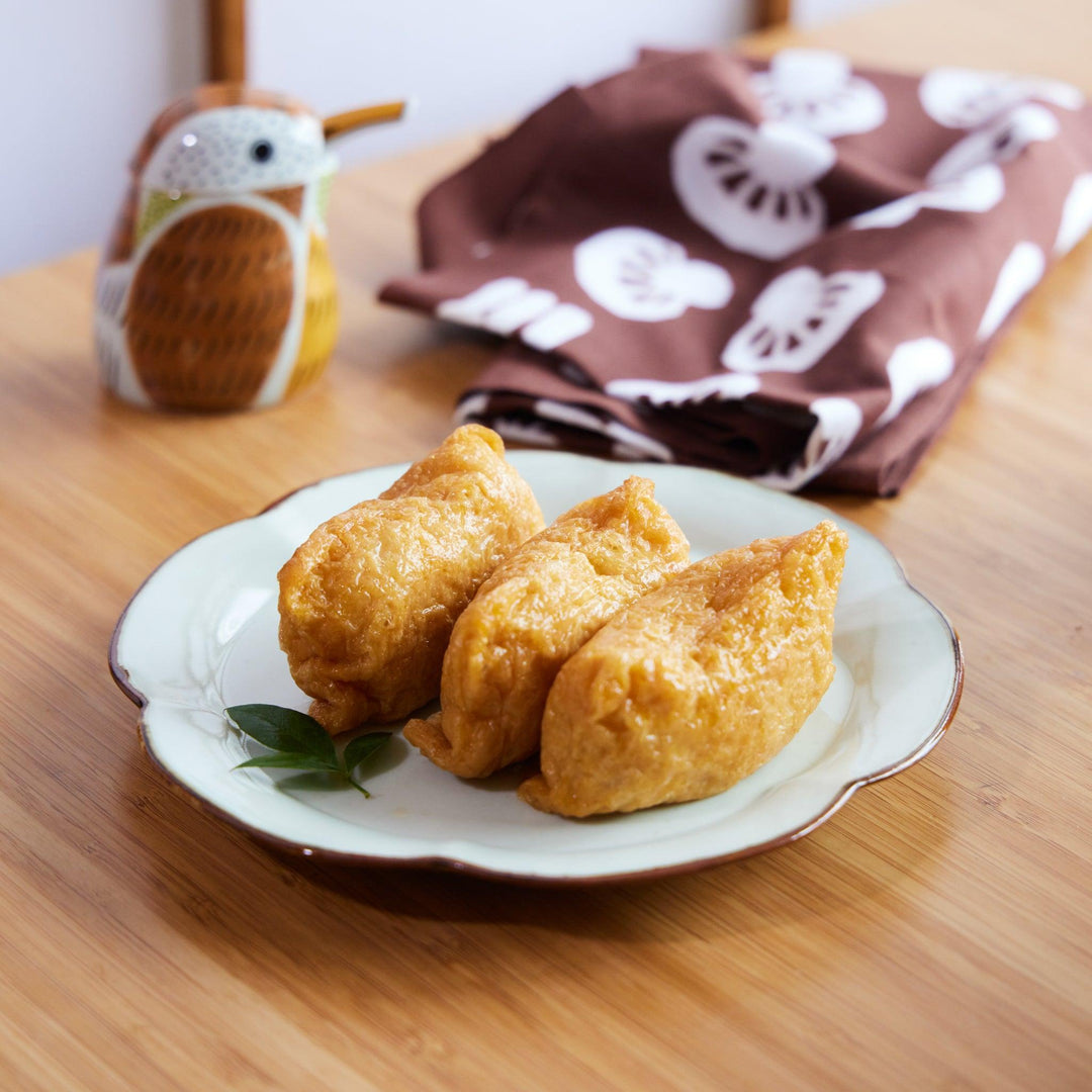 Rinka Flower Dessert Plate with three inari sushi, showcasing its delicate scalloped edge and elegant white glaze.