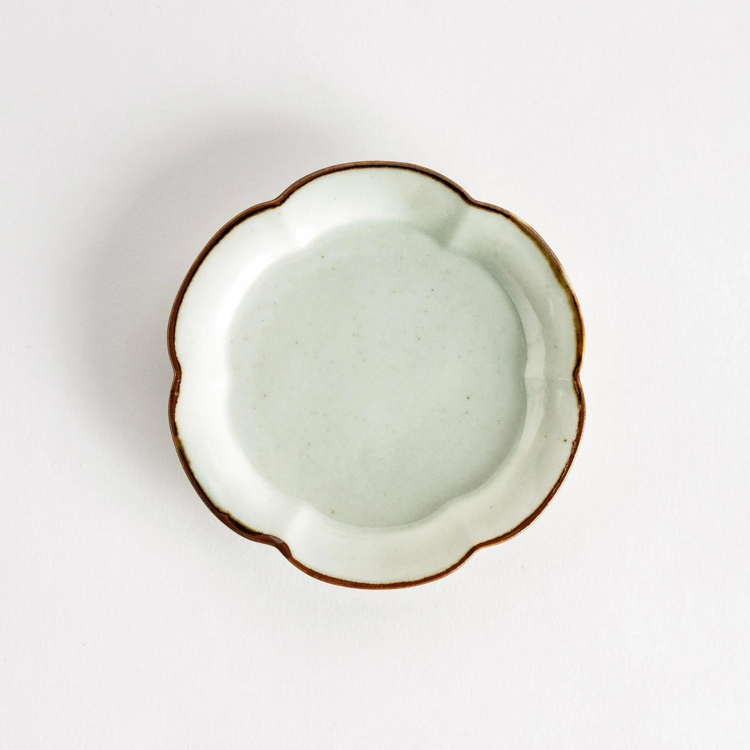 Small flower-shaped sauce dish in green, brown, and white.