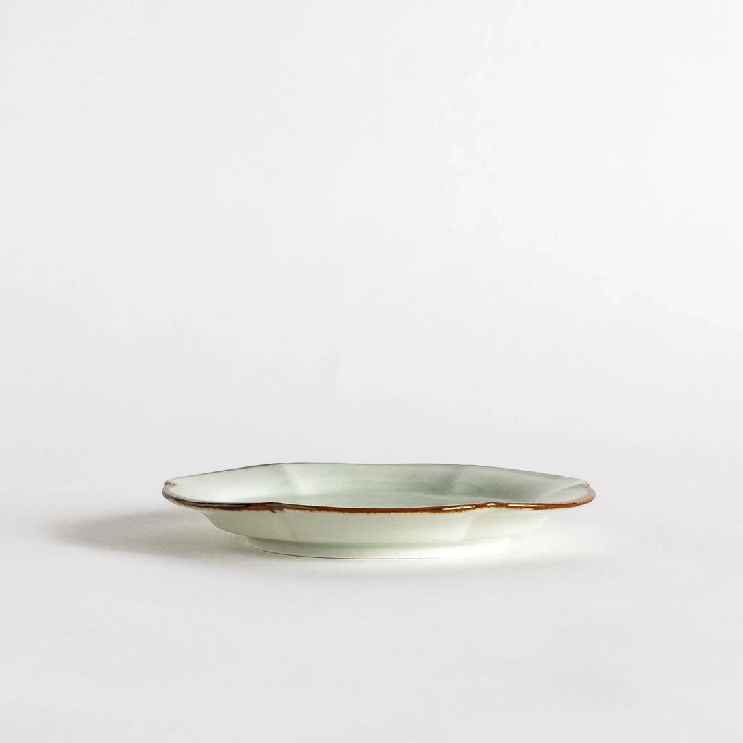 Small flower-shaped sauce dish in green, brown, and white.