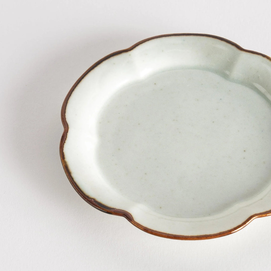 Small flower-shaped sauce dish in green, brown, and white.