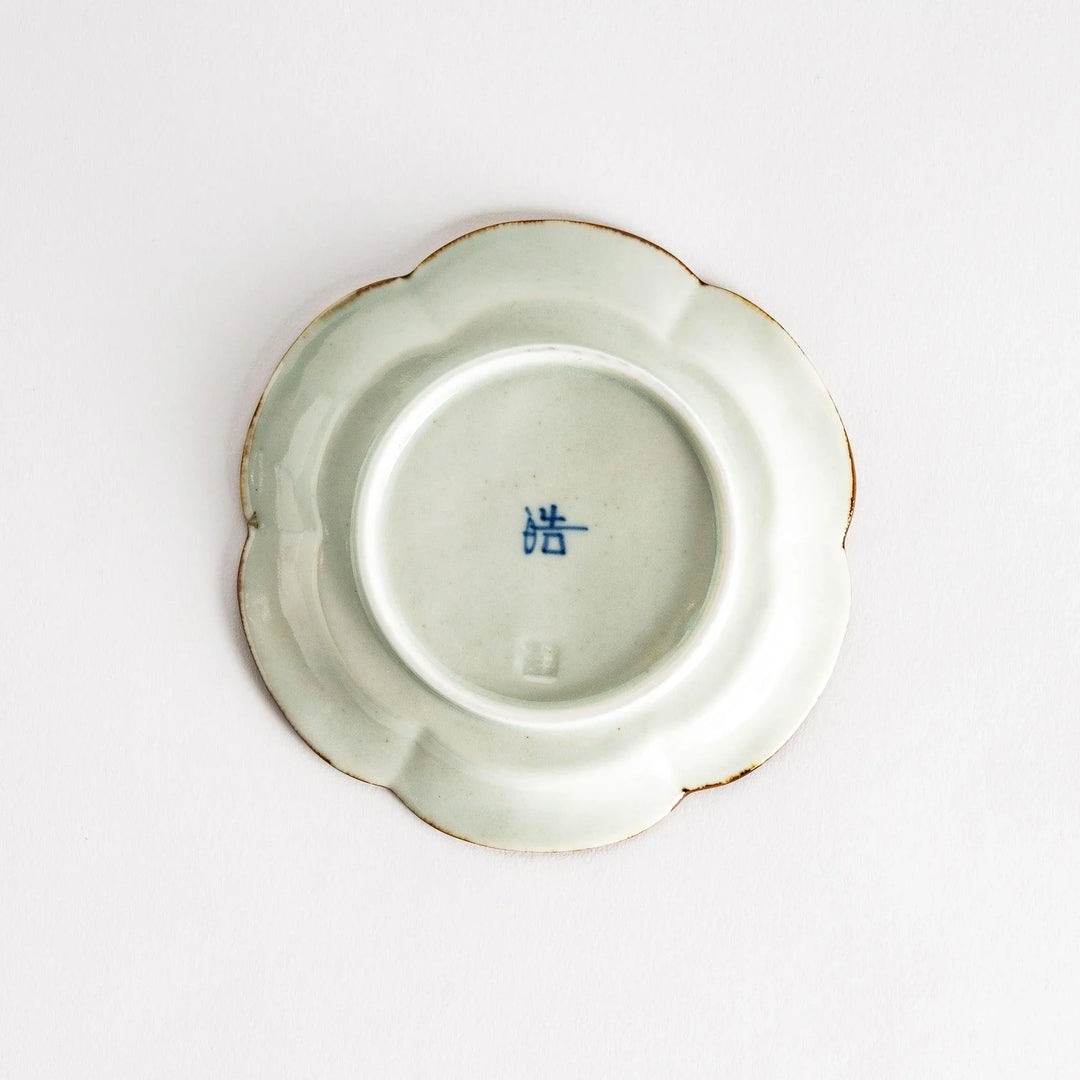 Small flower-shaped sauce dish in green, brown, and white.