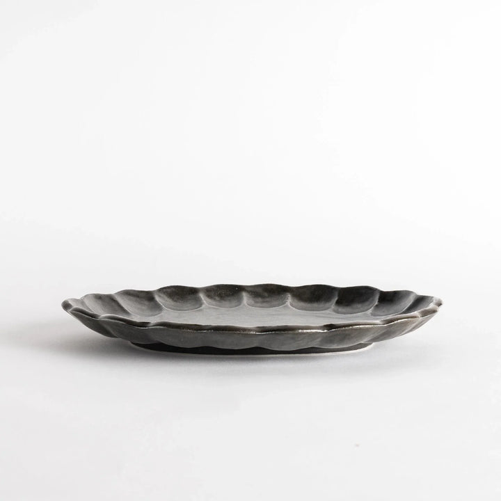 A white ceramic serving plate with a delicate, scalloped oval shape. Available in black or white.